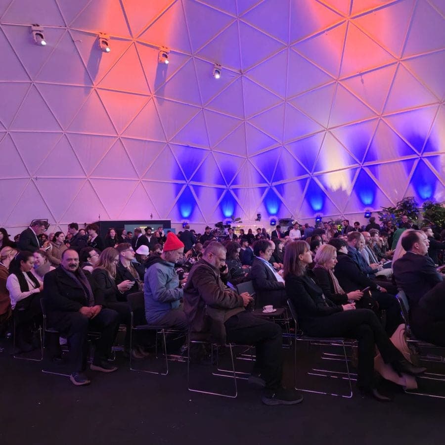 A full conference audience under a lit dome