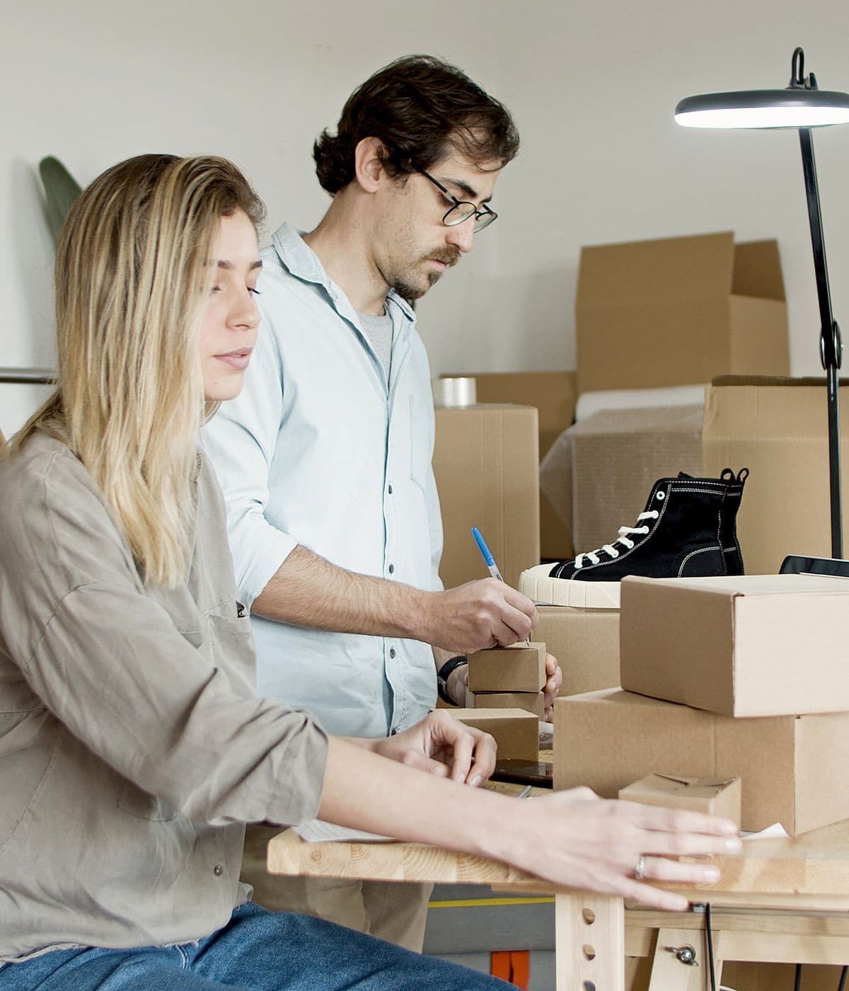 Two small-business founders labelling and packing product boxes at a workbench