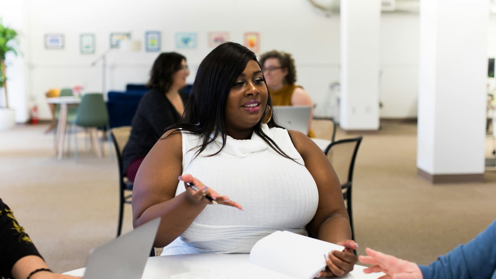 A business owner talking with colleagues across a table in a shared workspace